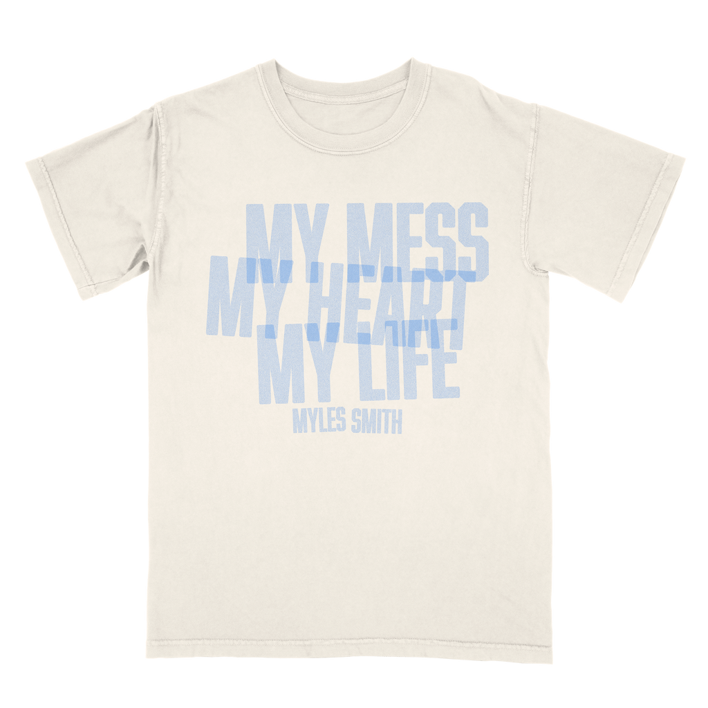 Front view of an ivory unisex short-sleeve T-shirt with blue text across the front reading ‘My Mess, My Heart, My Life,’ and smaller text below reading ‘Myles Smith.