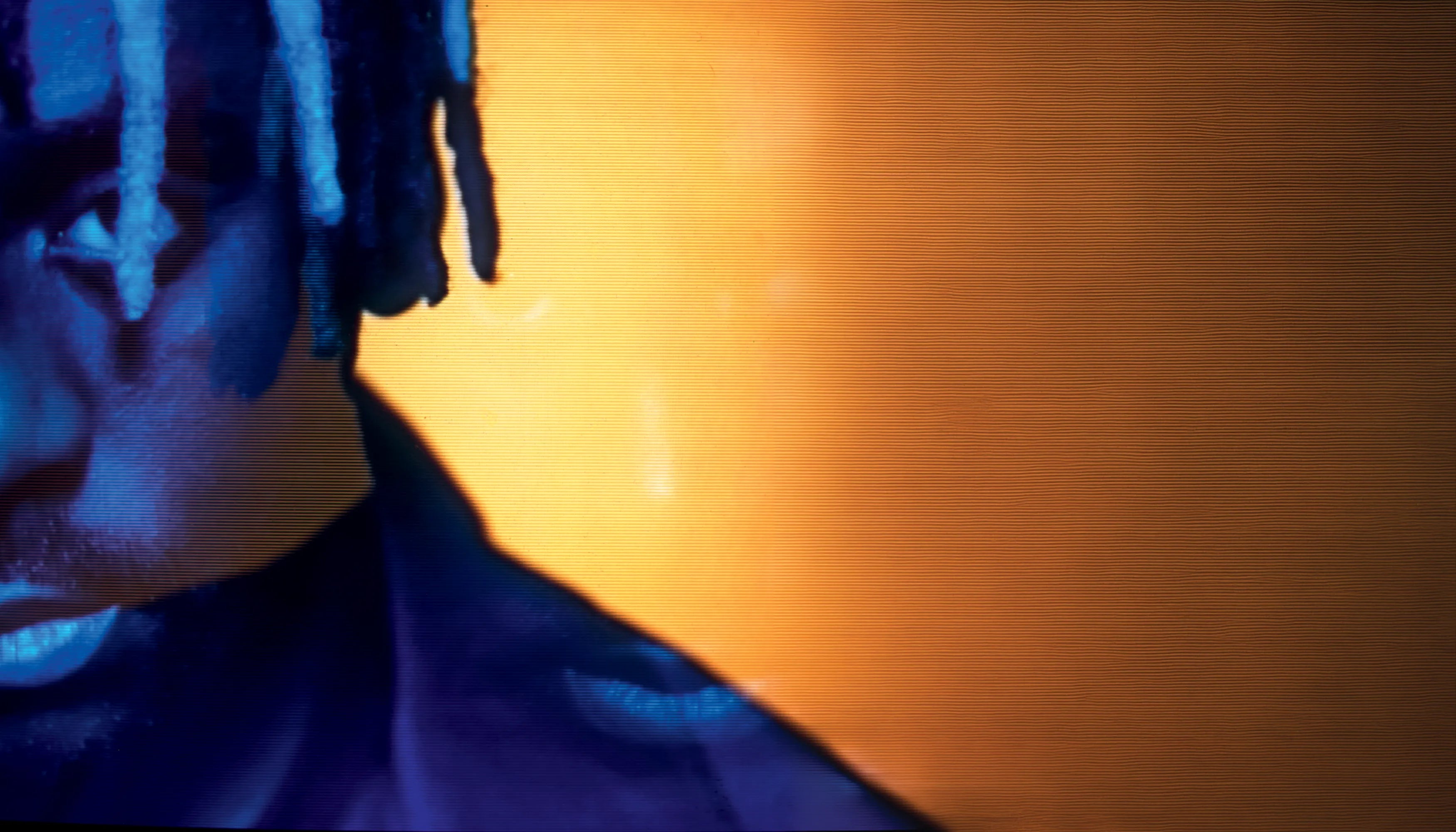 Close-up of Myles Smith, lit in blue tones against a warm orange background.